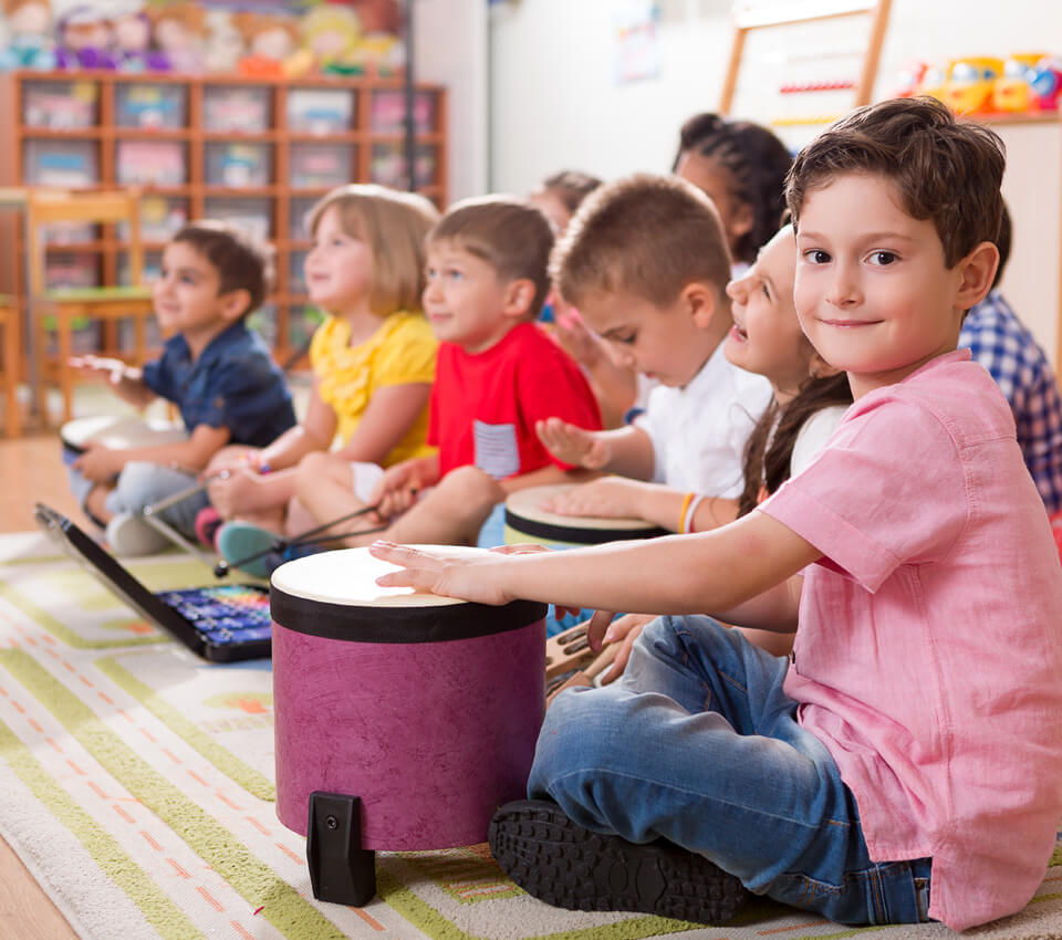 Preschool classroom filled with happy children playing kid-friendly instruments.
