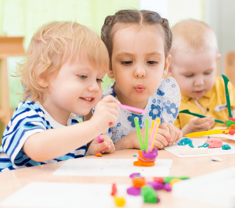 Toddler-aged children playing with colorful modeling clay during daycare.